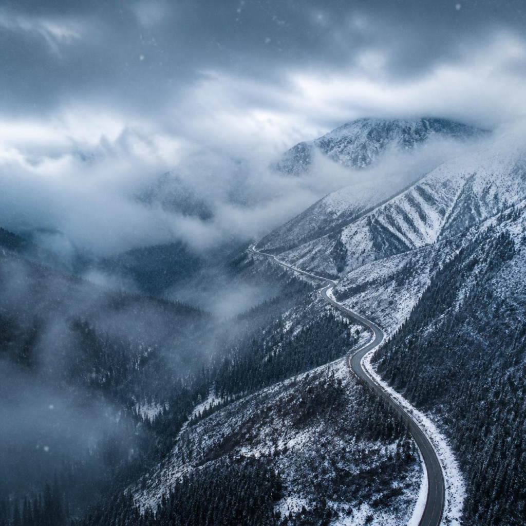 Fresh snowfall covering mountain terrain and highways in northern Alaska.